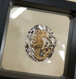 Seahorse w/grass pendant, 30mm, rhodium plated, .925 sterling silver, 18Kt gold plating highlighting this adorable seahorse. Sold with an 18” rhodium plated, sterling silver chain.  Authorized reproduction of an original museum quality Rainforest Design®️handcrafted shell cameo, carved in Panama by a master Wounaan Indian artist. Part of the proceeds go to the artist whose signature appears on the reverse.   Shipped in suspension frame box with gift ready cover. 
