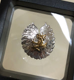 Frog on lily pad pendant, 30mm, rhodium plated, .925 sterling silver, 18Kt gold plating on frog. Sold with an 18” sterling silver chain. Authorized reproduction of an original museum quality Rainforest Design®️handcrafted shell cameo, carved in Panama by a master Wounaan Indian artist. Part of the proceeds go to the artist whose signature appears on the reverse. The Panama Golden Frog or Rana Dorada, is now extinct in the wild,