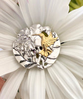 Hummingbird w/ hibiscus flower pendant, 25 mm, rhodium plated, .925 sterling silver with 18Kt gold plating accenting the hummingbird. Sold with a 18” rhodium plated sterling silver chain.  Authorized reproduction of an original museum quality Rainforest Design®️handcrafted shell cameo, carved in Panama by a master Wounaan Indian artist. Part of the proceeds go to the artist whose signature appears on the reverse. 