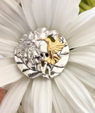 Hummingbird w/ hibiscus flower pendant, 25 mm, rhodium plated, .925 sterling silver with 18Kt gold plating accenting the hummingbird. Sold with a 18” rhodium plated sterling silver chain.  Authorized reproduction of an original museum quality Rainforest Design®️handcrafted shell cameo, carved in Panama by a master Wounaan Indian artist. Part of the proceeds go to the artist whose signature appears on the reverse. 
