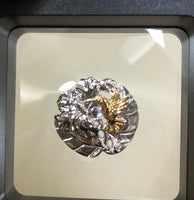 Hummingbird w/ hibiscus flower pendant, 25 mm, rhodium plated, .925 sterling silver with 18Kt gold plating accenting the hummingbird. Sold with a 18” rhodium plated sterling silver chain.  Authorized reproduction of an original museum quality Rainforest Design®️handcrafted shell cameo, carved in Panama by a master Wounaan Indian artist. Part of the proceeds go to the artist whose signature appears on the reverse. 